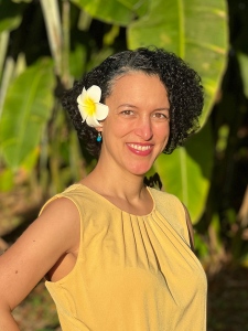 Historical romance author Erica Ridley, Caucasian woman with dark curly hair wearing a yellow dress with a flower behind her ear.
